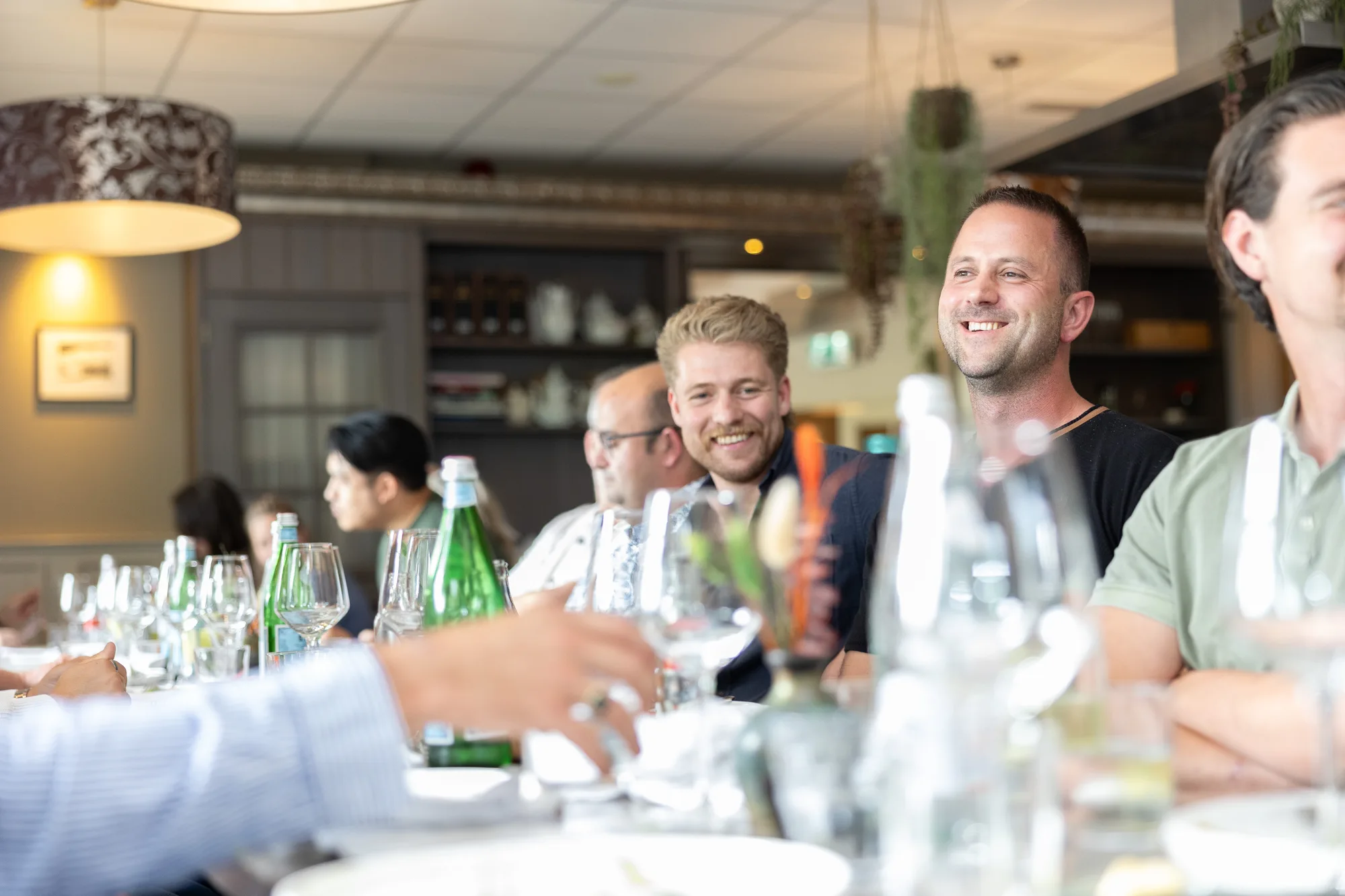 Lachende deelnemers en begeleiders tijdens een gezamenlijk teamdiner